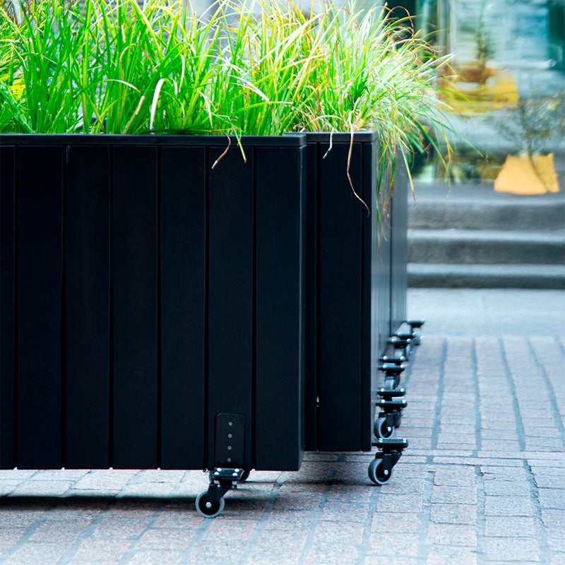 Jardinera de madera con ruedas, ideal para separar espacios en terrazas y jardines, con dimensiones de 100x24x80 cm.